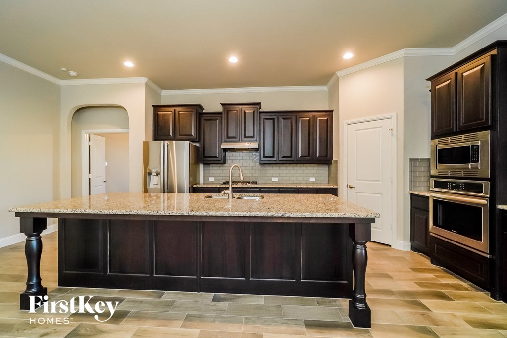 a kitchen with dark wood cabinets and a marble counter top