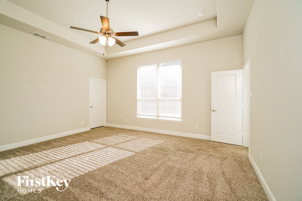 a spacious living room with carpet and a ceiling fan