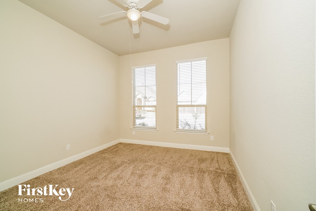 the spacious living room has carpeting and a ceiling fan