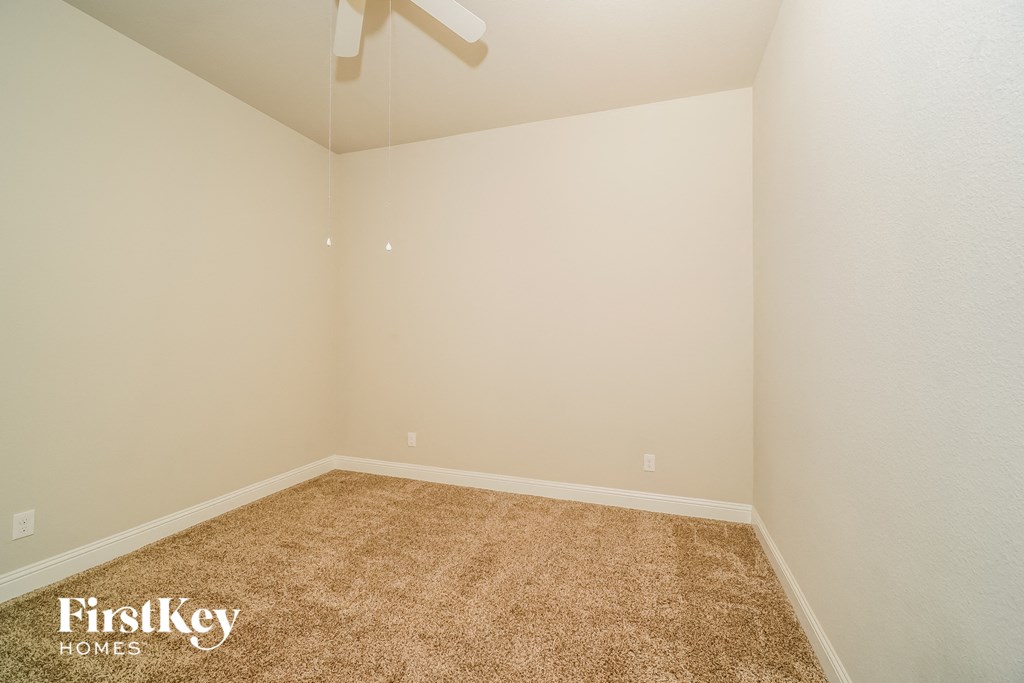 a empty room with carpet and a ceiling fan