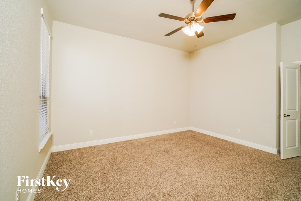 a empty room with a ceiling fan and white walls