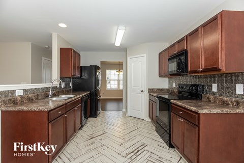 A kitchen with brown cabinets and a black refrigerator.