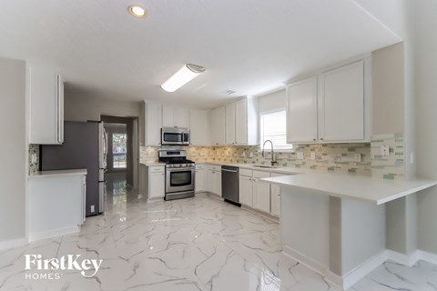 a large kitchen with white cabinets and marble flooring