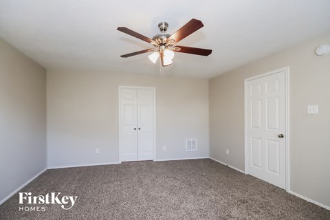 the spacious living room with ceiling fan and white doors