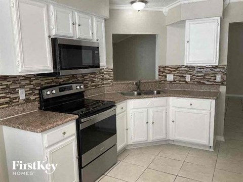 A kitchen with a black stove top oven and a black microwave above a counter with a granite counter top.