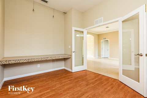 a living room with a hardwood floor and an open door to a hallway with