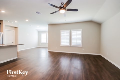 an empty living room with wood floors and a ceiling fan