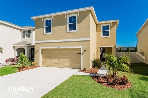 a beige house with a garage door and a lawn