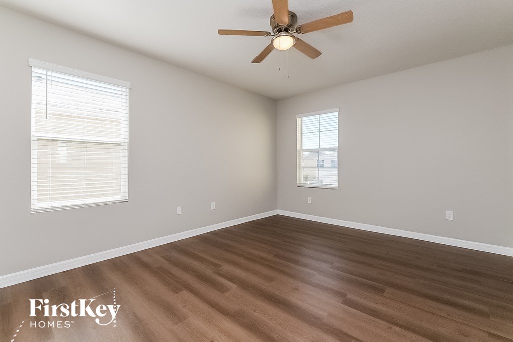 the spacious living room with hardwood flooring and a ceiling fan
