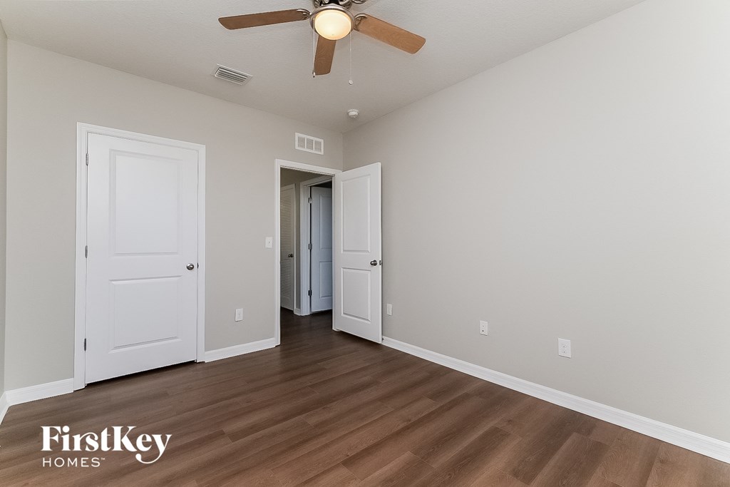 a bedroom with a ceiling fan and a door to a closet