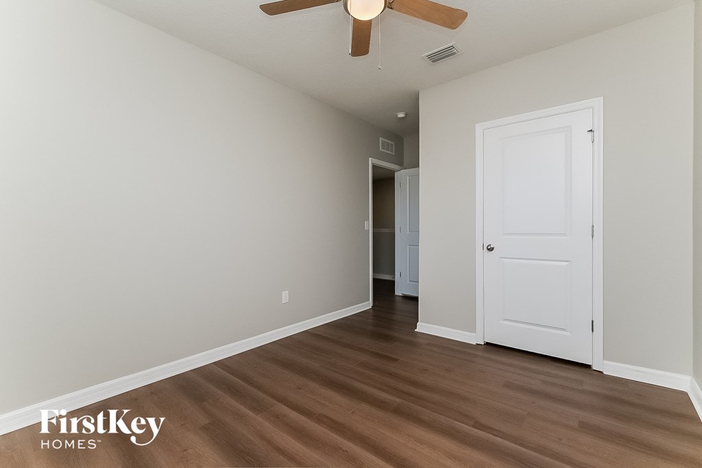 a living room with a white door and a ceiling fan