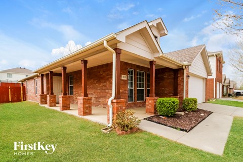 a brick house with a porch and a lawn