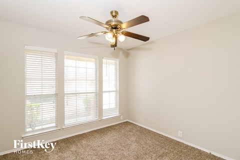 a bedroom with a ceiling fan and three windows