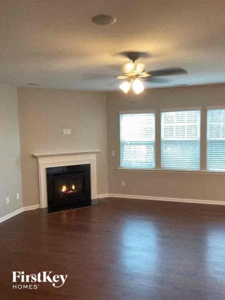 an empty living room with a fireplace and a ceiling fan