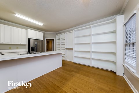 A kitchen with white cabinets and a wooden floor.