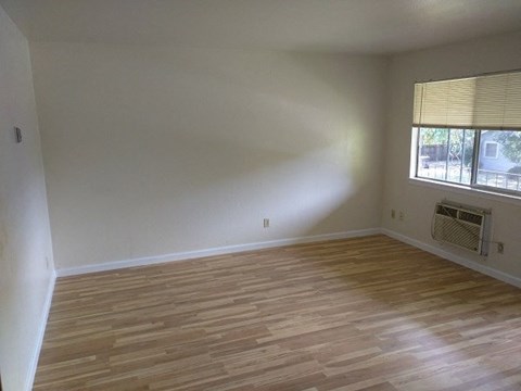 an empty living room with wooden floors and a window