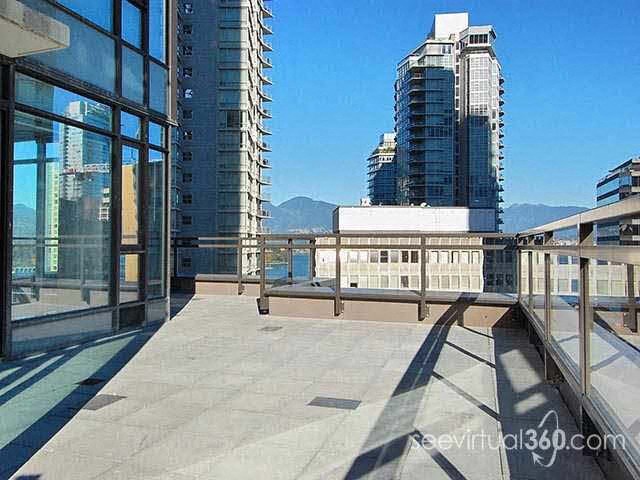 A balcony with a glass railing and a view of a cityscape.
