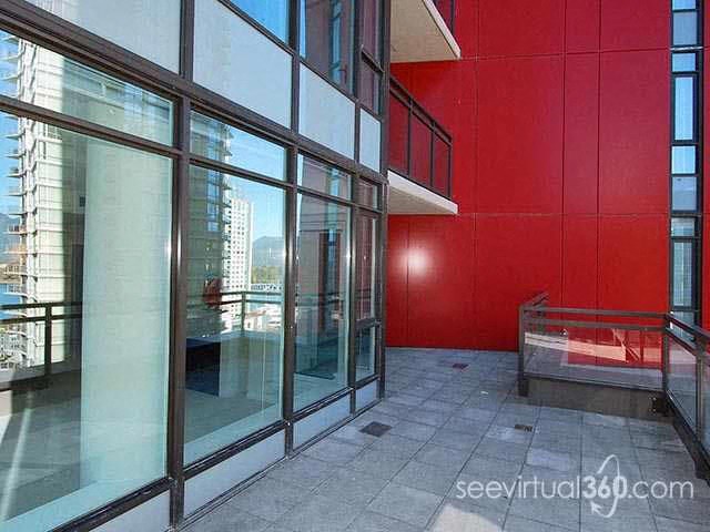 A balcony with glass doors and a red wall.