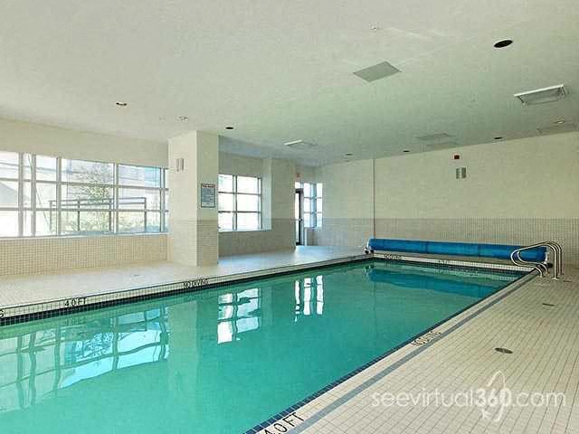 A large indoor swimming pool with a bench and windows.