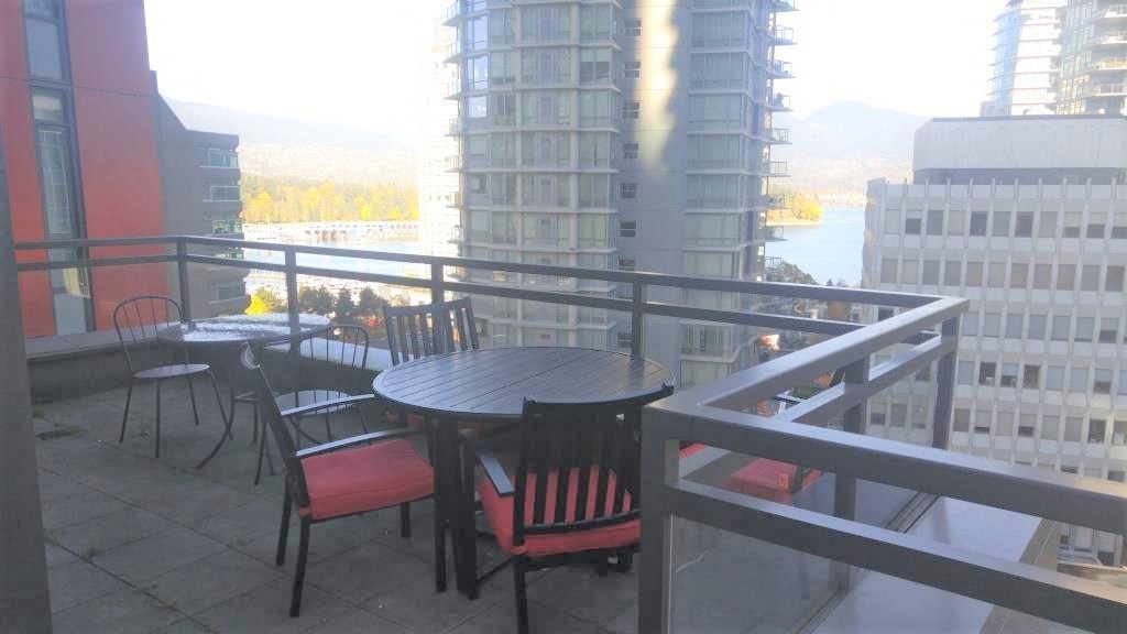 A balcony with a table and chairs overlooking a cityscape.