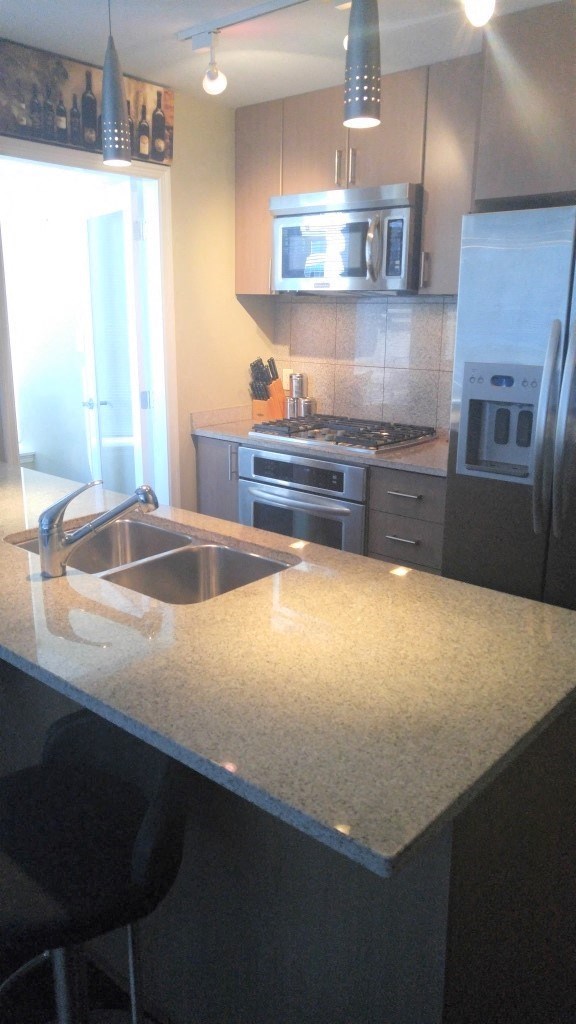 A kitchen with a granite countertop and stainless steel appliances.