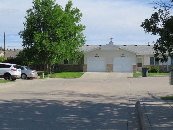 a white house with two garage doors and a parking lot