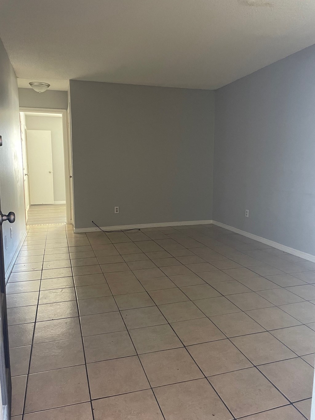 an empty living room with tiled floors and gray walls