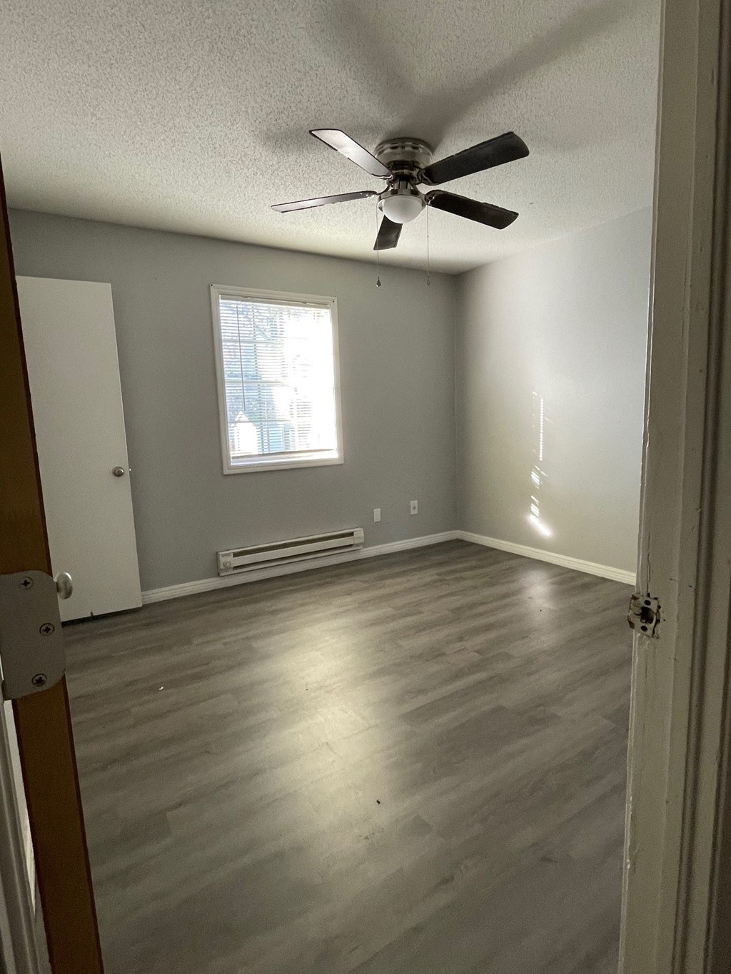 an empty room with wooden floors and a ceiling fan