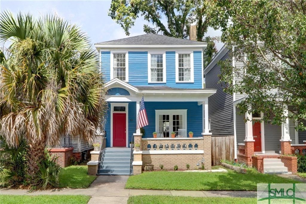 A blue house with a red door and a flag on the front porch.