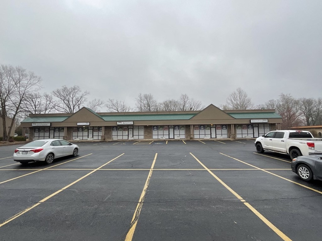 A parking lot with a building in the background and cars parked in the spaces.
