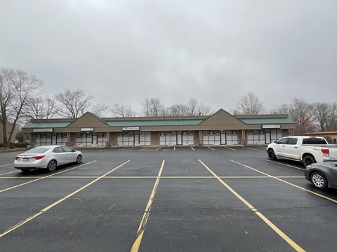 A parking lot with a building in the background and cars parked in the spaces.