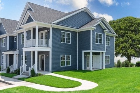 a blue house with a gray roof and a lawn