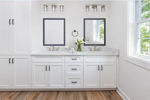 a white bathroom with two sinks and two mirrors