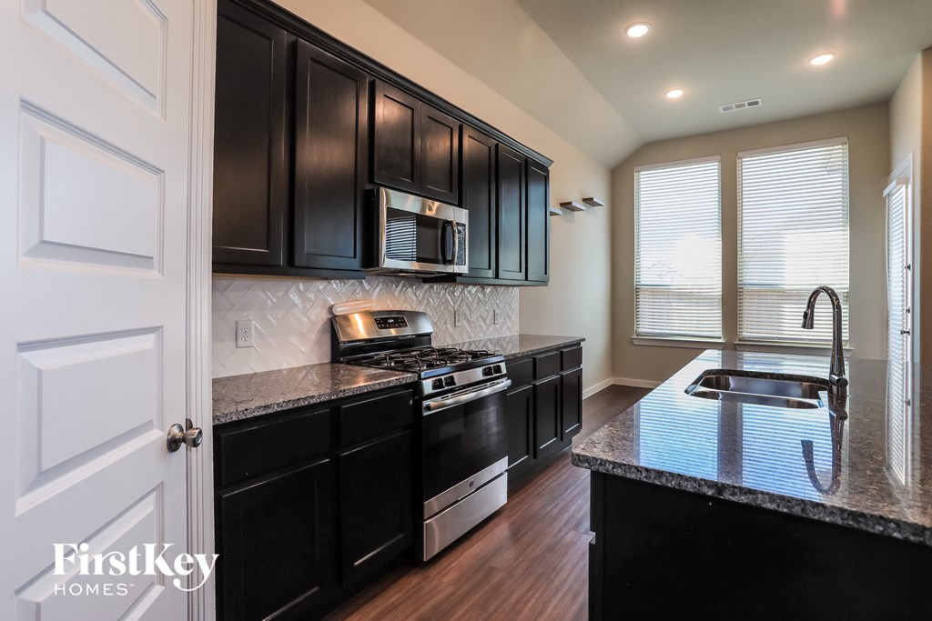 a kitchen with black cabinets and a counter top and a sink