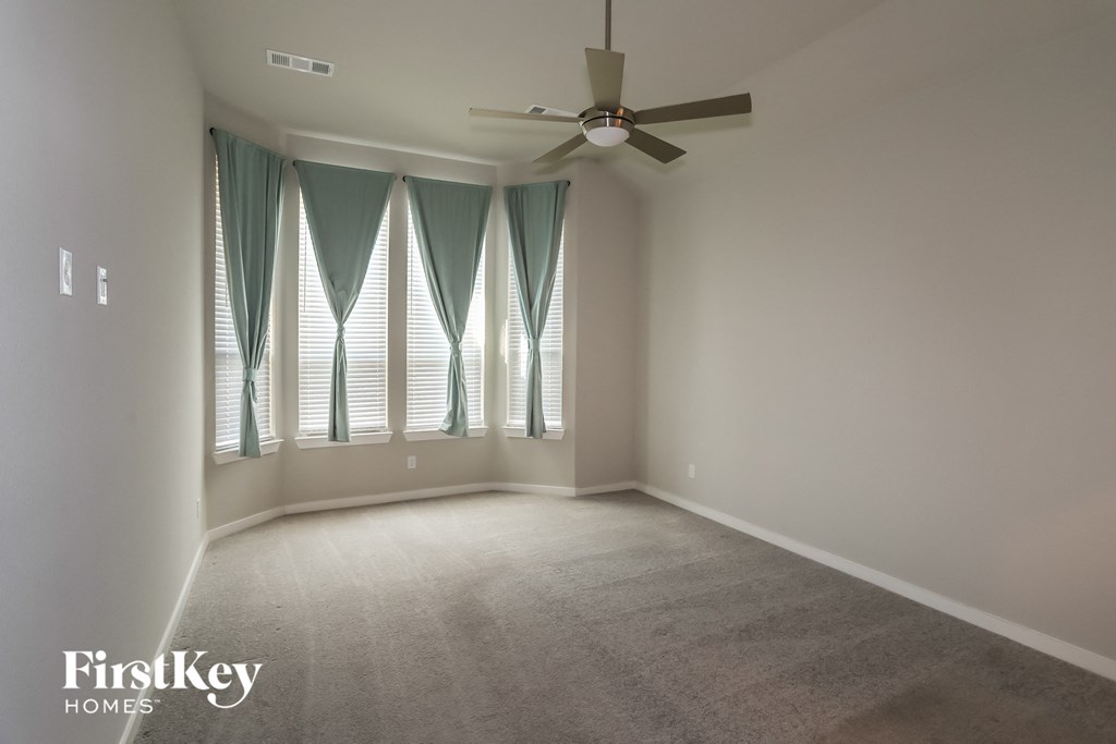 an empty living room with windows and a ceiling fan