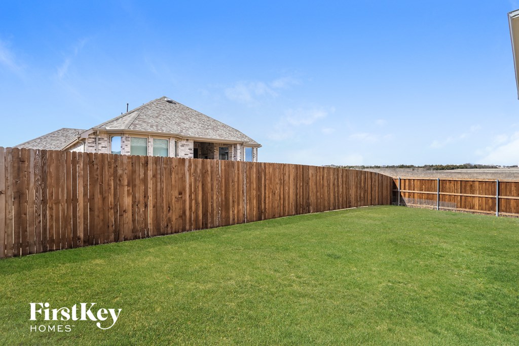 a backyard with a wooden fence and a house behind it