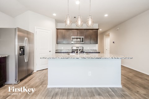 A modern kitchen with a stainless steel refrigerator and a white island.