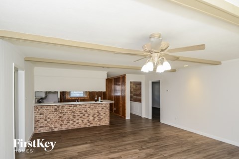 A spacious room with a ceiling fan and a brick wall.
