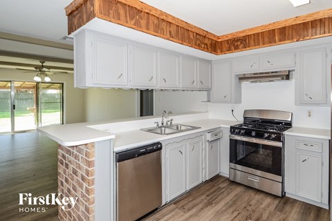 A kitchen with white cabinets and a wooden ceiling.