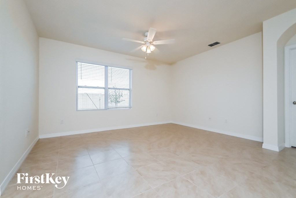 a spacious living room with white walls and a ceiling fan