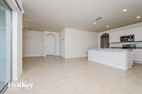 an open kitchen and living room with white cabinets and tile flooring