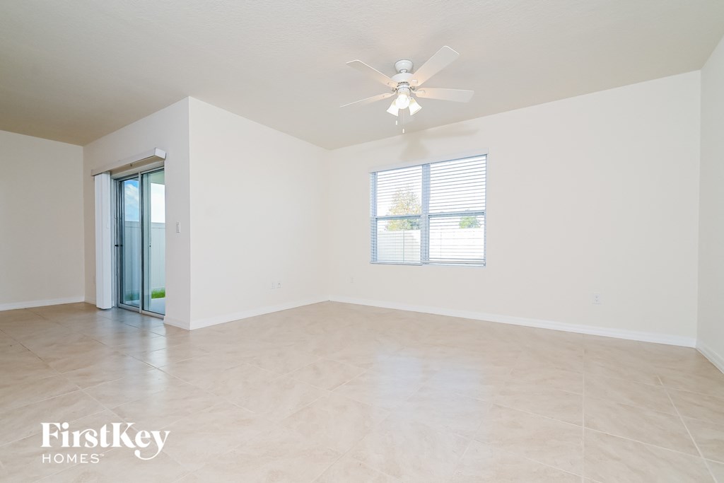 a spacious living room with white walls and a ceiling fan
