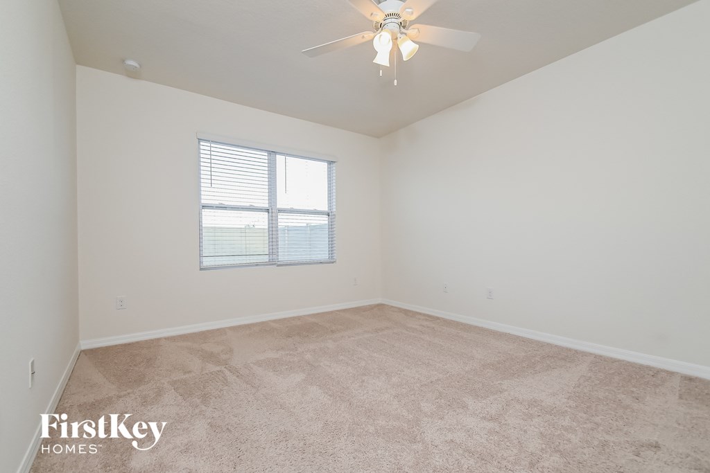a bedroom with carpet and a ceiling fan and a window