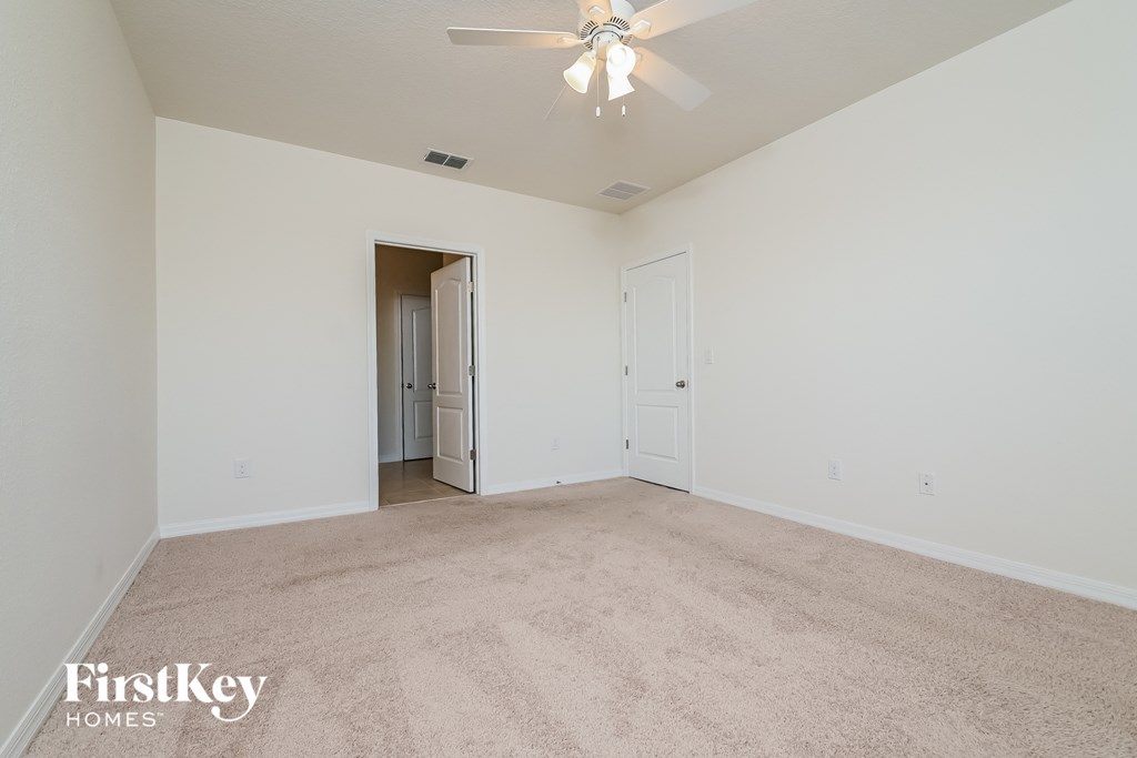 a spacious living room with carpeting and a ceiling fan