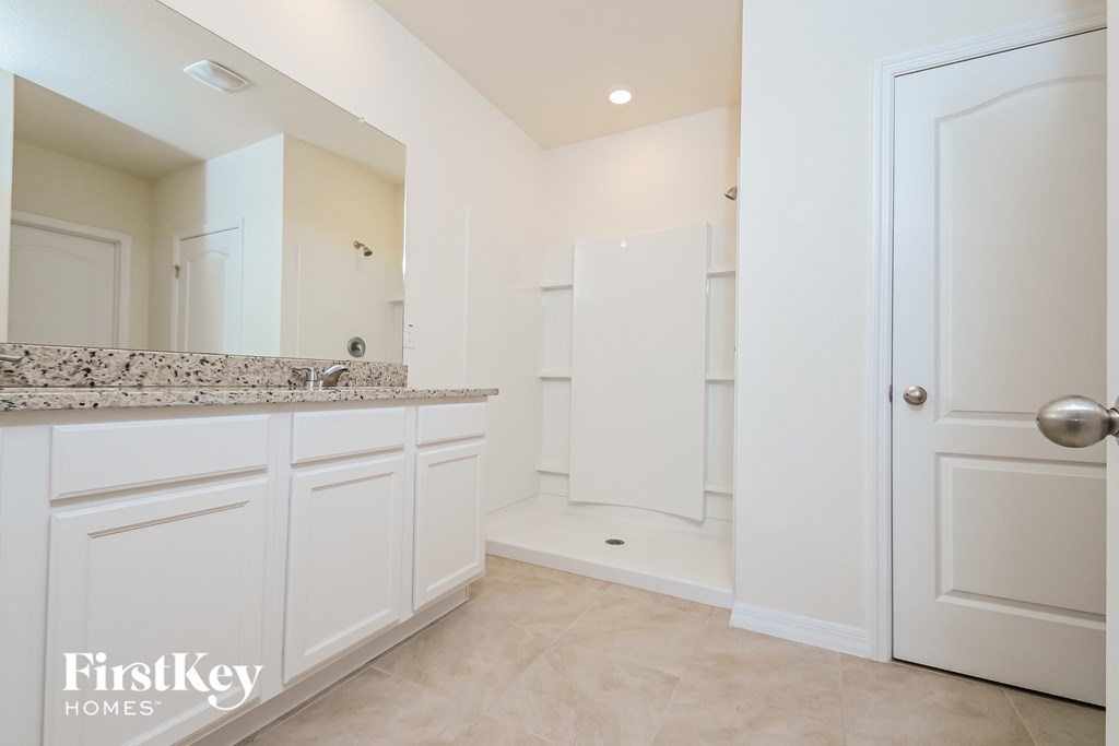 a large white bathroom with white cabinets and a large mirror
