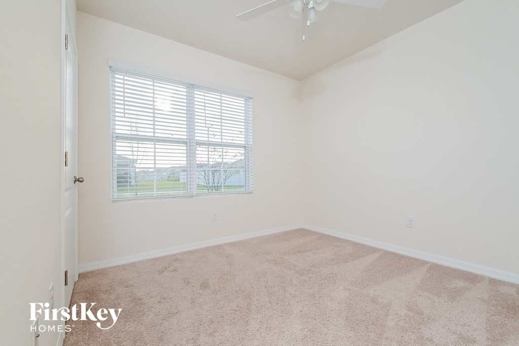a bedroom with a large window and beige carpet