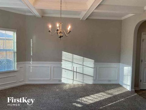 an empty dining room with a chandelier and window