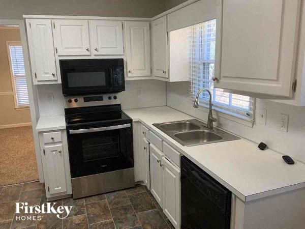 A kitchen with white cabinets and a black microwave.