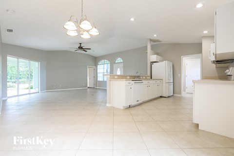 an open kitchen and living room with white cabinets and tile floors