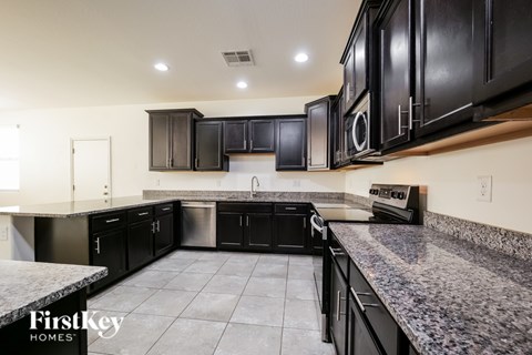 A kitchen with black cabinets and granite countertops.